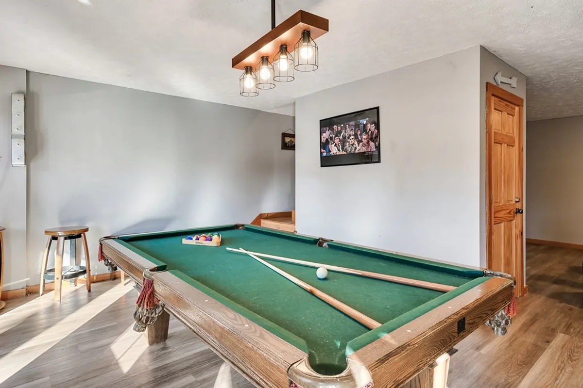 A lively interior game room scene showcasing a sleek pool table, modern lighting fixture, and wall art. The space is designed for casual competition and group entertainment, echoing the section’s focus on friendly games and memorable group experiences.